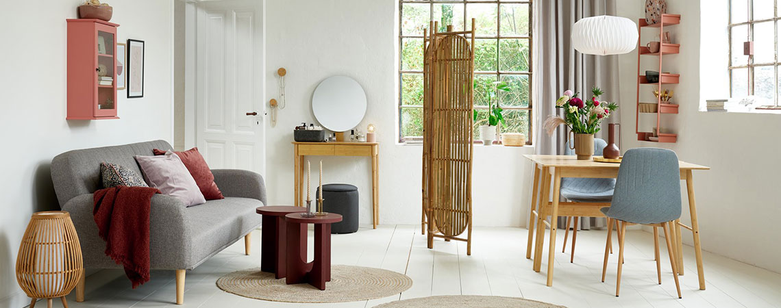 Salón-comedor con armario de pared rosa, sofá-cama gris, biombo de bambú, escritorios de bambú y sillas de comedor grises 