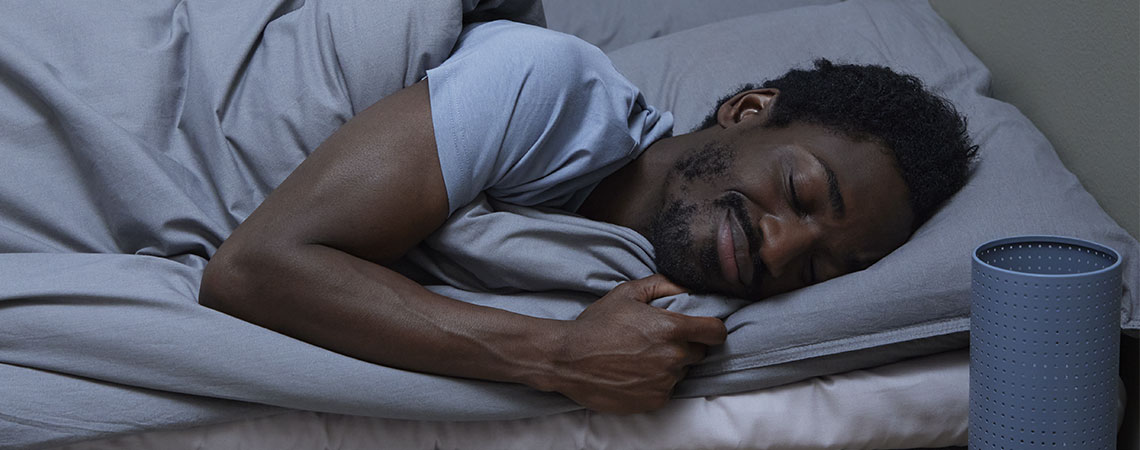 Hombre durmiendo en cama con almohada y edredón grises