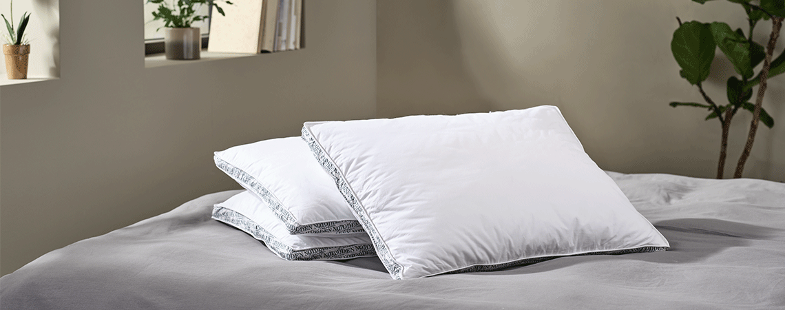 Tres almohadas en una cama con ropa de cama gris 
