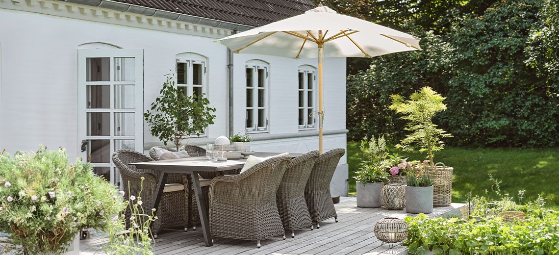Sombrilla de jardín en la zona de terraza de un jardín con una mesa y sillas de jardín 