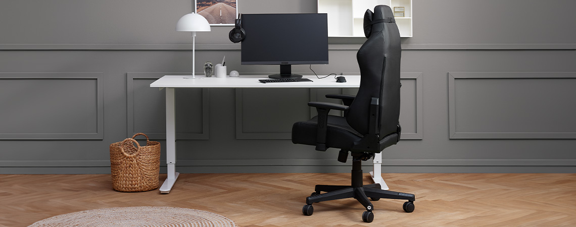 Silla gaming elegante y ergonómica al lado de un escritorio con monitor y auriculares