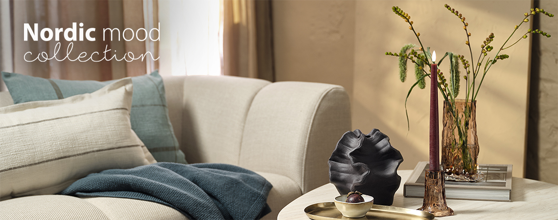 Salón con sofá y mesa de centro con un jarrón de cristal y un candelabro