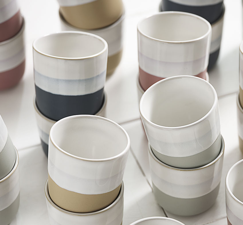 Taza de porcelana con bandas de distinto color en varios tonos 
