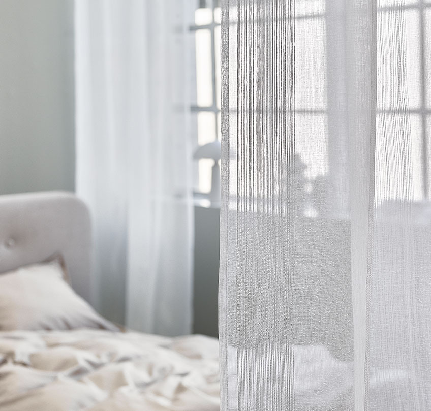 Cortinas blancas utilizadas para separar una zona de dormitorio de una sala de estar