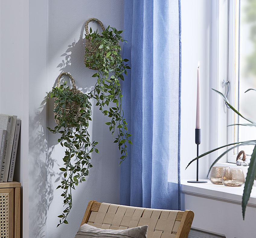 Cesta INGVER con planta artificial OLIVER Dos cestas con plantas artificiales colgando de la pared de un salón