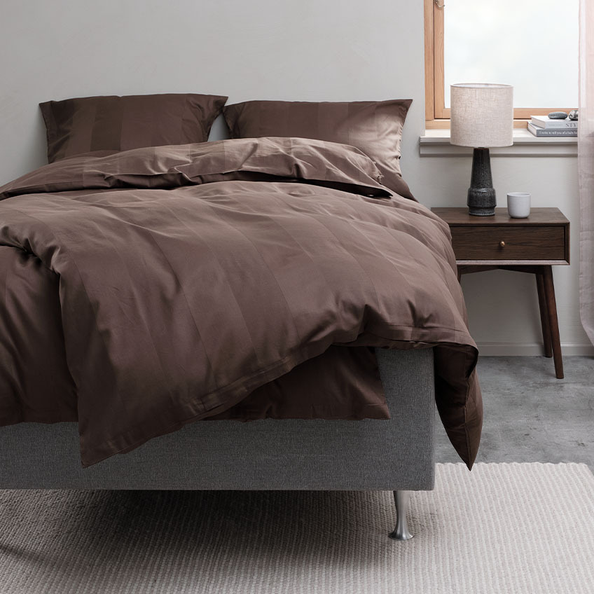 Juego de funda nórdica de color marrón chocolate y ropa de cama en una cama de un dormitorio
