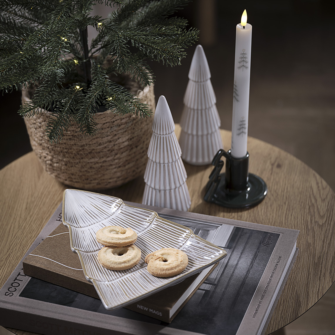 Bandeja decorativa con galletas, dos árboles decorativos y portavelas con una vela sobre una mesa