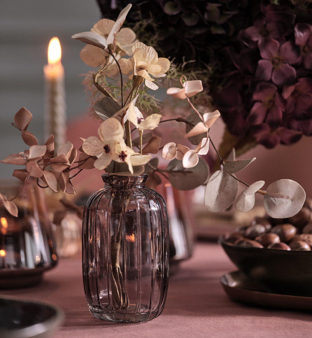 Jarrón de cristal gris con flores artificiales sobre una mesa