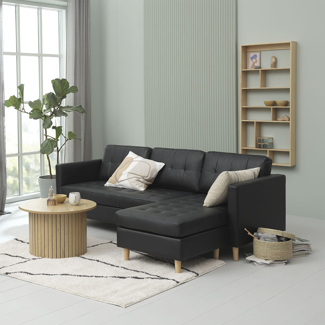 Sofá negro con chaise longue de polipiel con muebles de madera 