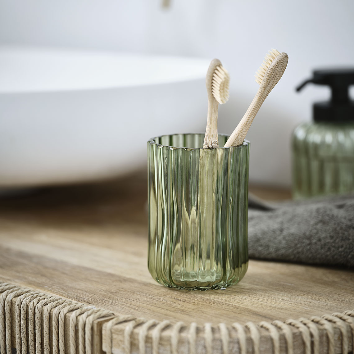 Portacepillos de dientes de cristal verde en un baño