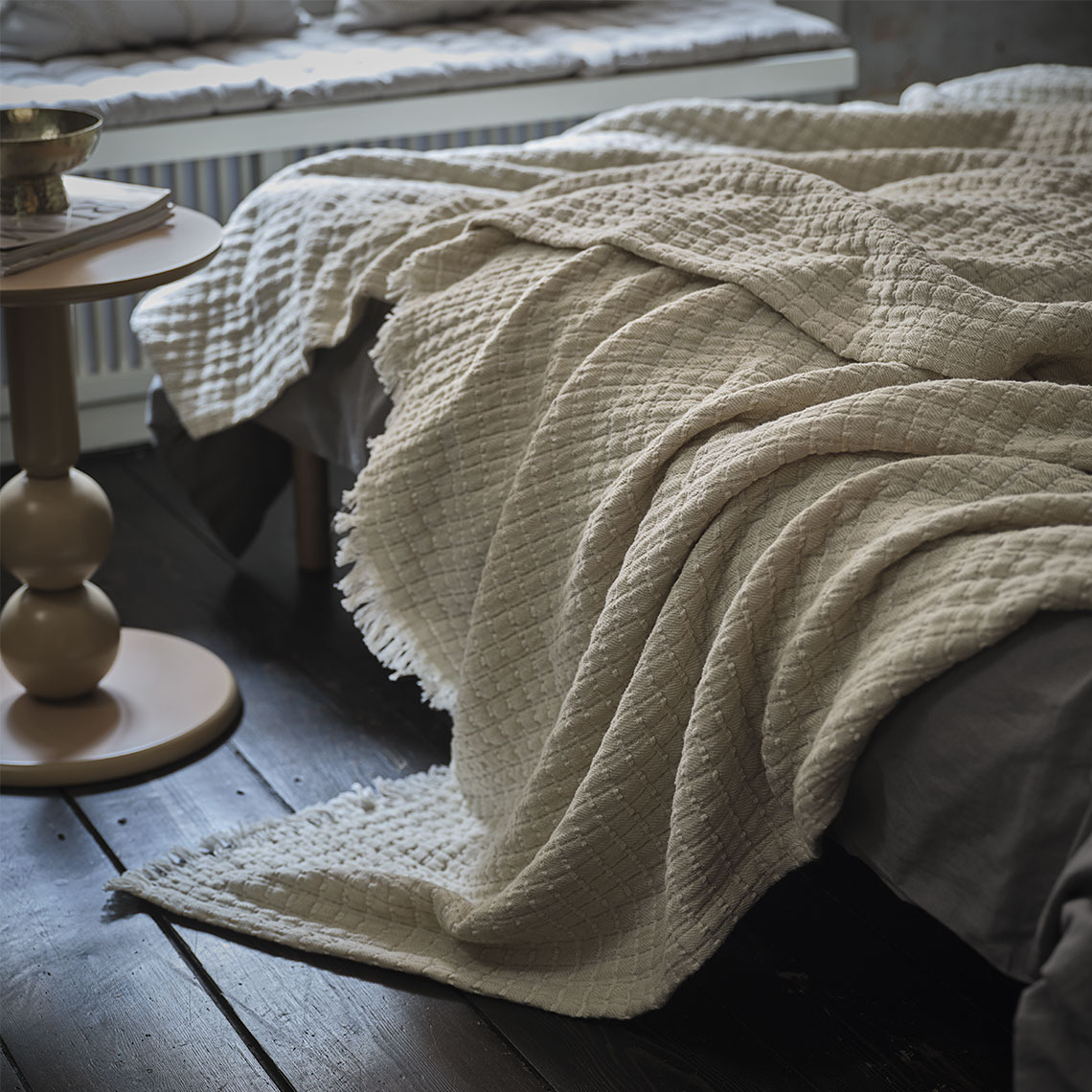 Colcha beige en la cama de un dormitorio