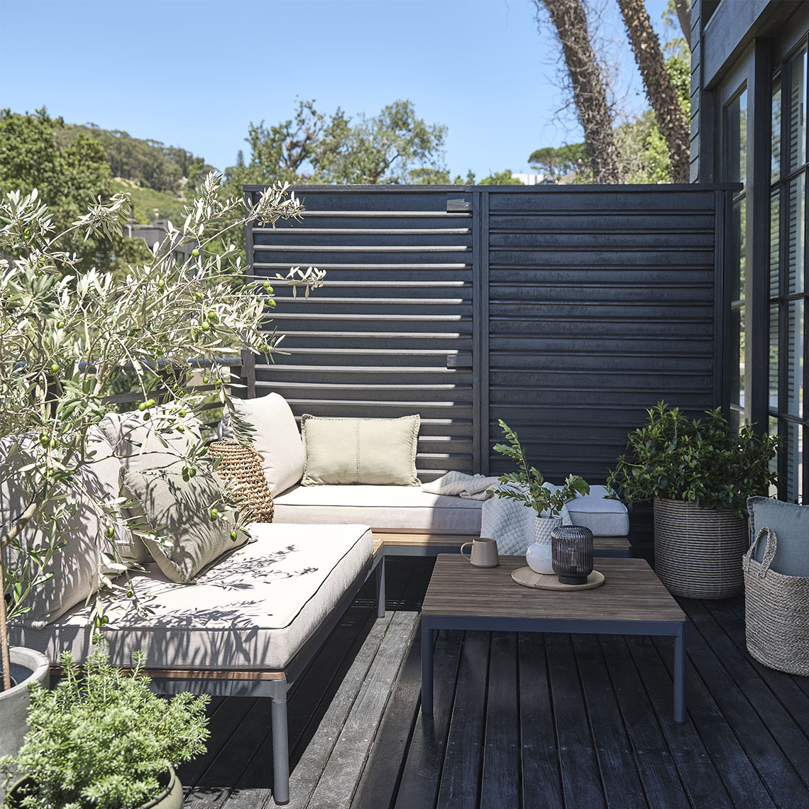 Conjunto de muebles de jardín en terraza pequeña con plantas y maceteros
