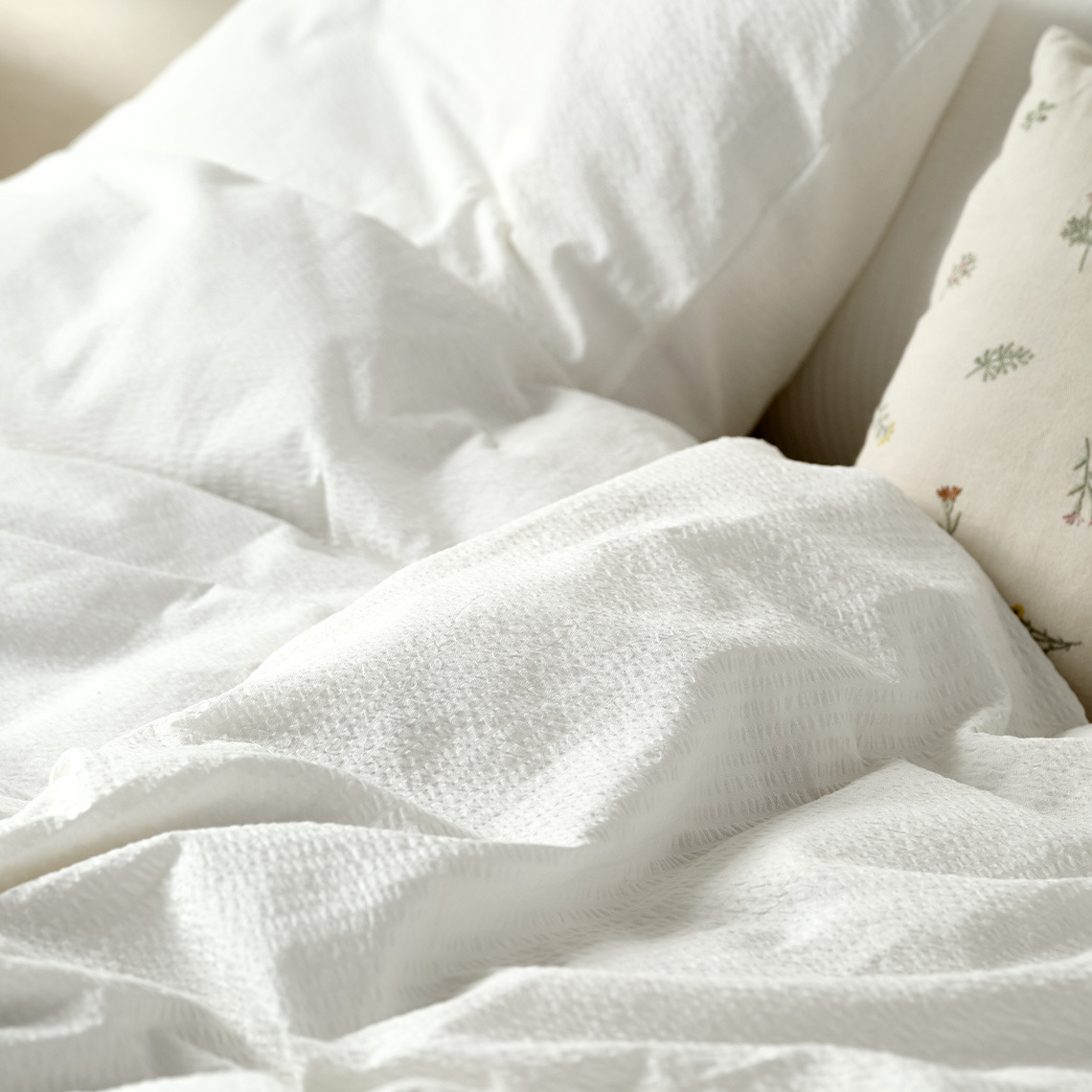 La ropa de cama hecha de tela de milrayas es excelente para mantenerse fresco durante toda la noche Ropa de cama blanca de milrayas sobre la cama