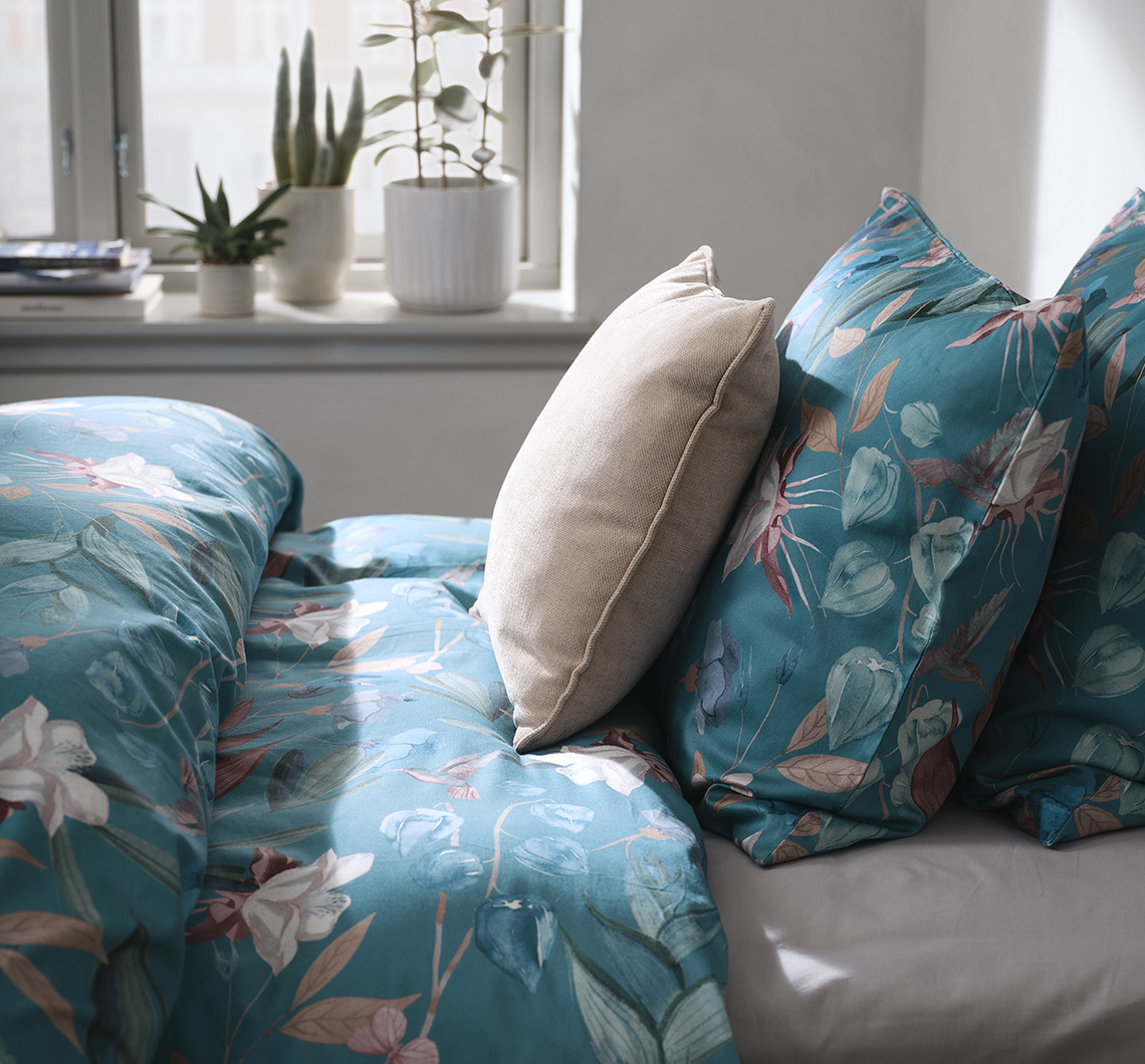 Combina BERTHA con prendas monocromáticas que contrasten para conseguir un aspecto dinámico. Dormitorio con ropa de cama de flores y almohada extra que contrasta con el color