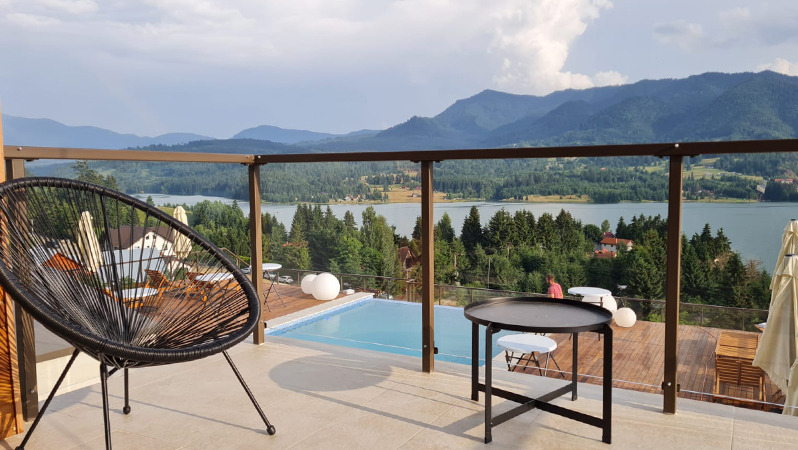 Un área al aire libre con una cómoda silla lounge de JYSK, con vista a las montañas y al lago.