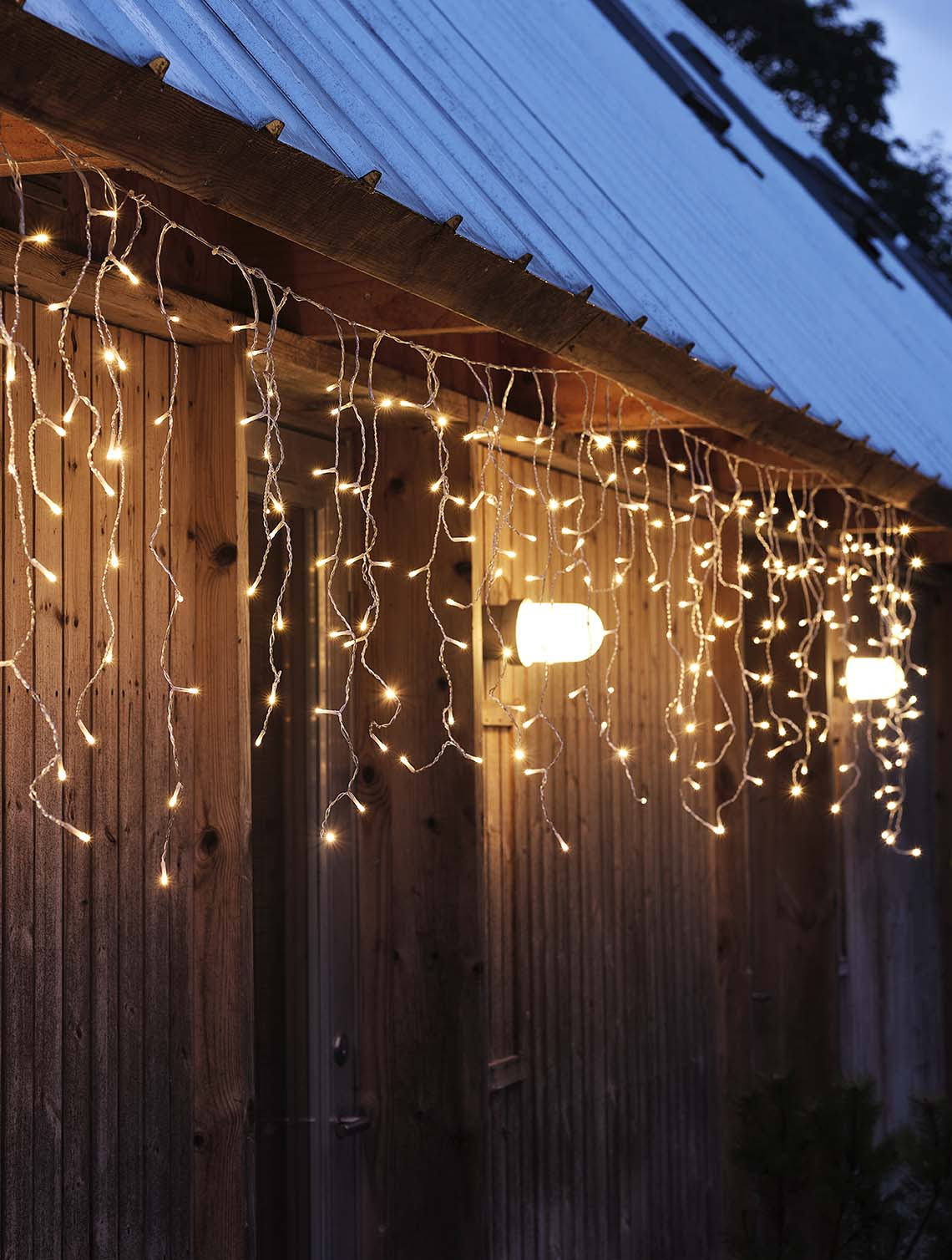 Guirnalda de luces brillando en la oscuridad, colgando de la fachada de una casa