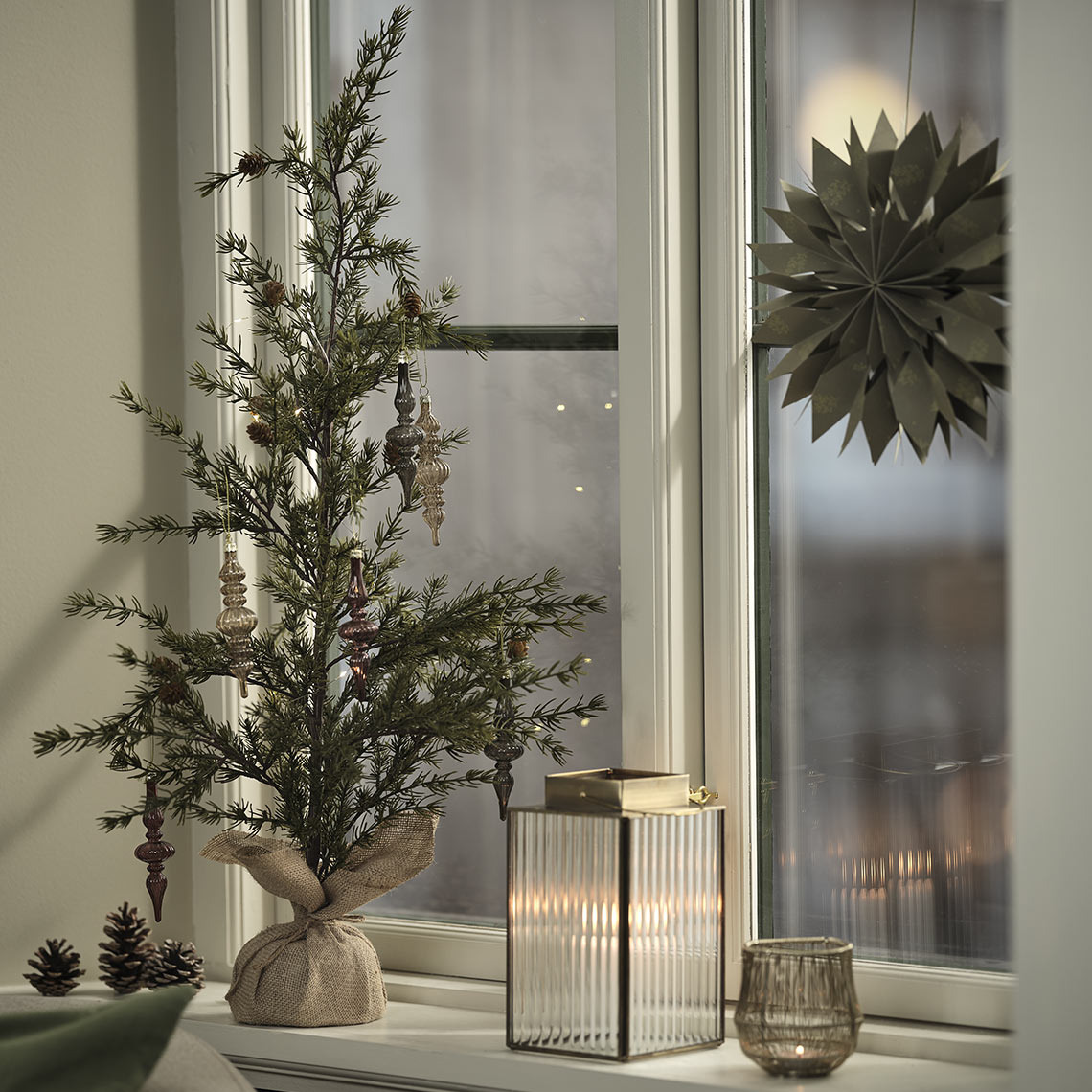 Portavelas, farol y árbol artificial de Navidad con decoraciones sobre una cornisa
