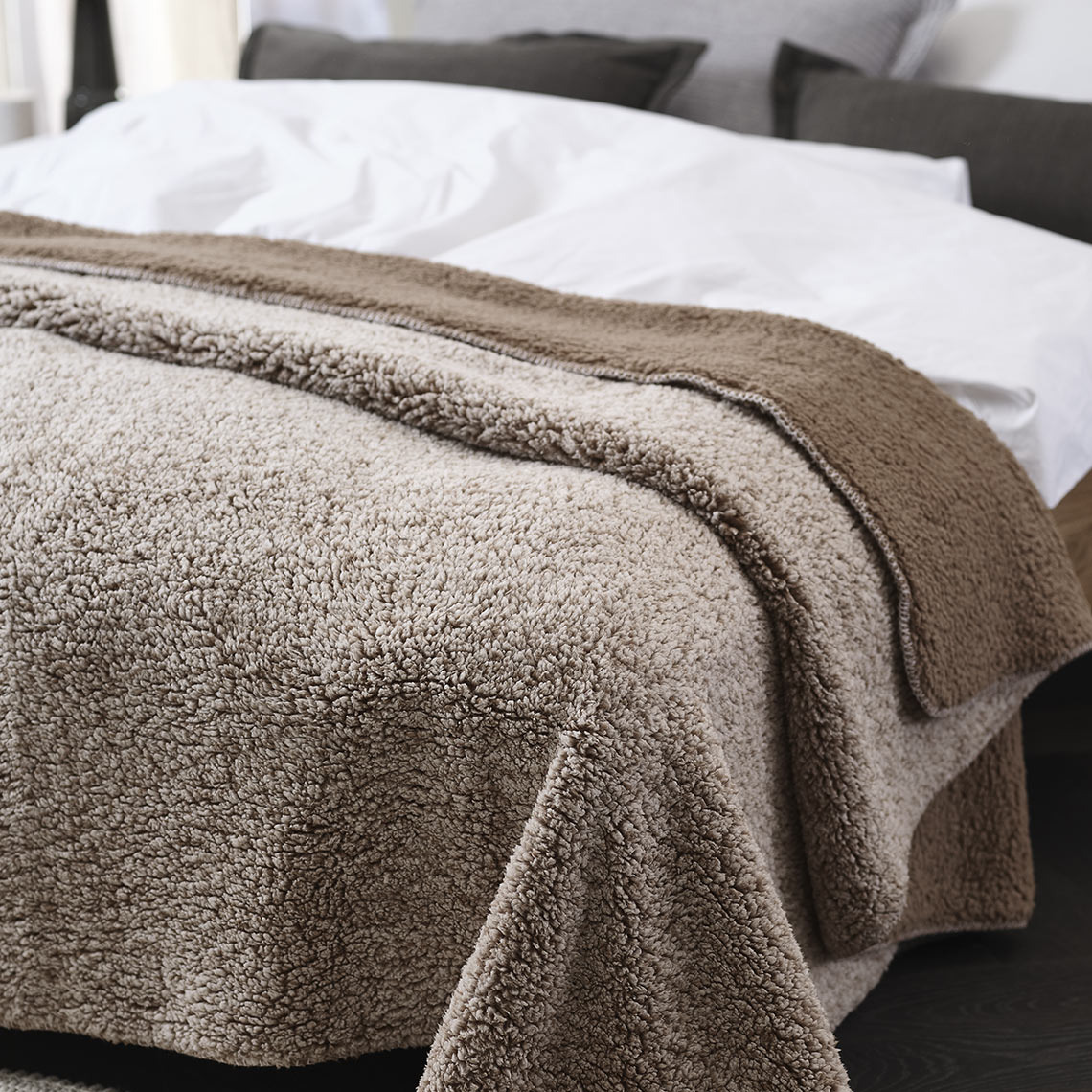 Manta de forro marrón en la cama de un dormitorio 