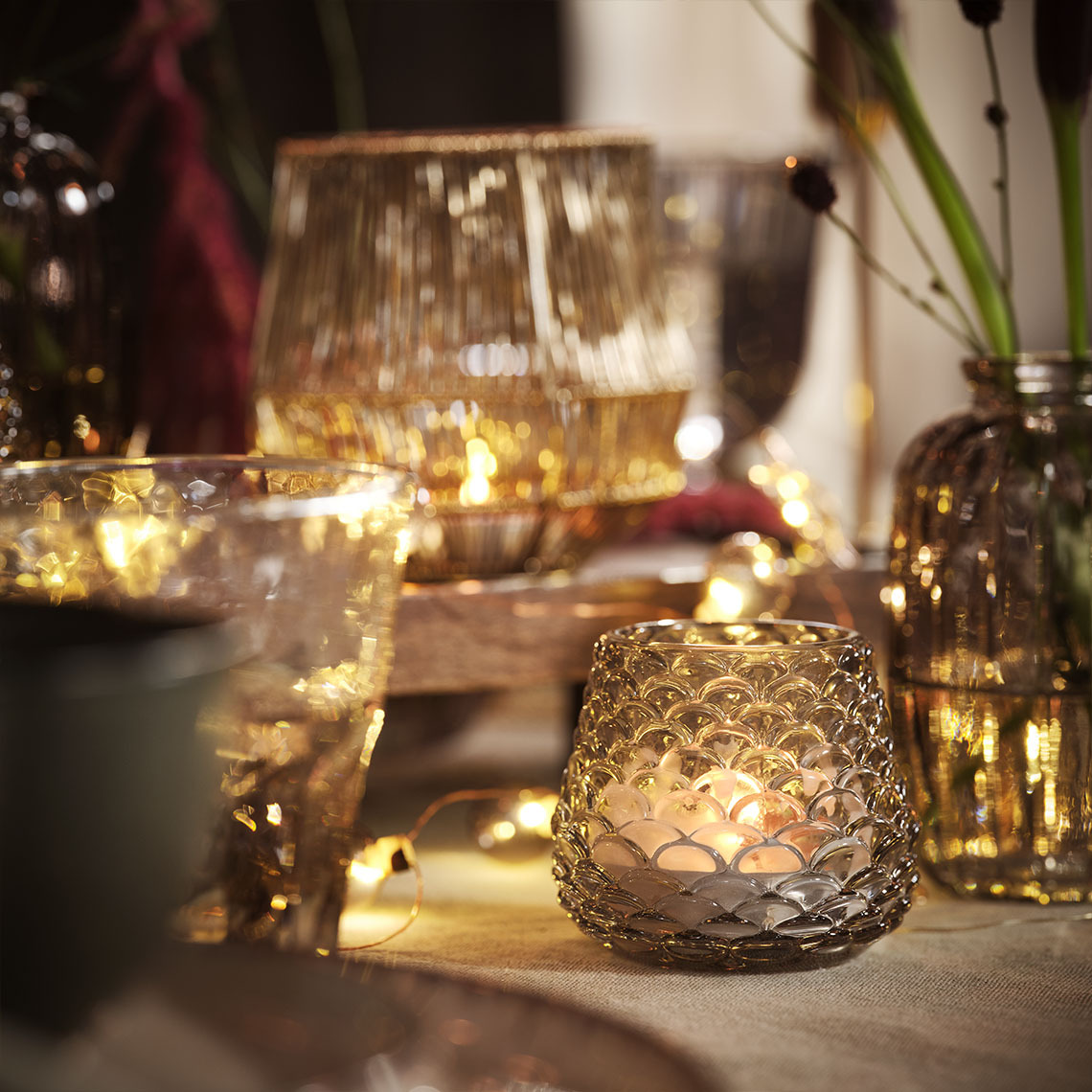 Mesa iluminada con velas y portavelas y guirnaldas de luces