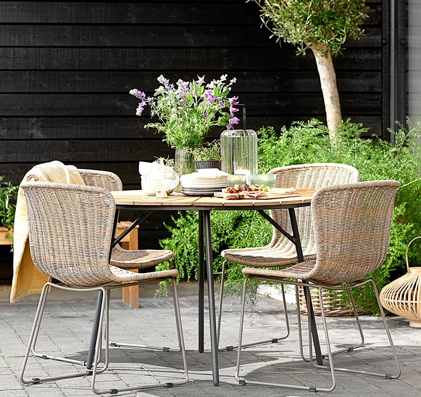 Cuatro sillas apilables alrededor de una mesa redonda de jardín en una terraza