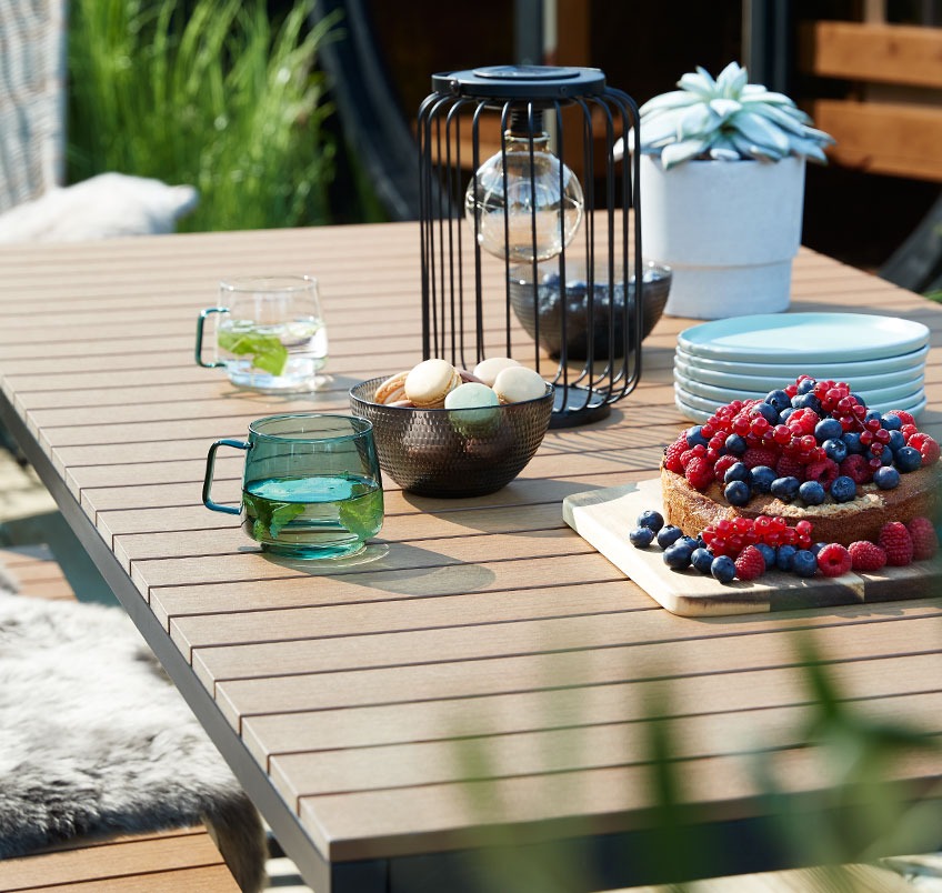 Mesa de jardín con galletas, café y tazas 