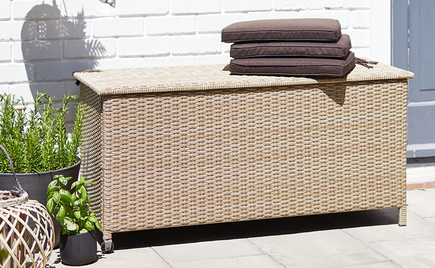 Caja de cojines YDERUP con ruedas y asa Caja de cojines con asa y ruedas en un patio soleado