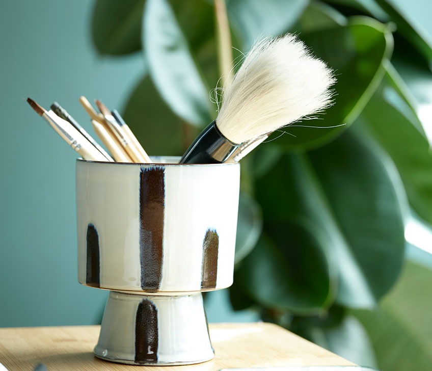 Plant pot with paint brushes on a bamboo desk