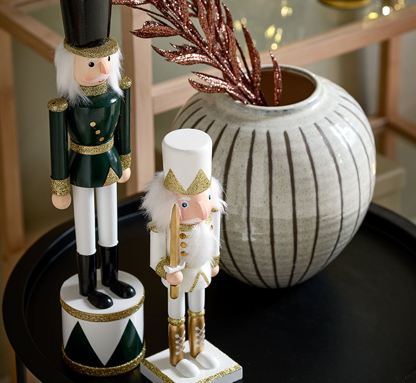 VALI and EUKLAS nutcracker figurines and SOFUS vase on RANDERUP end table Two Christmas figurines and a vase on a black end table