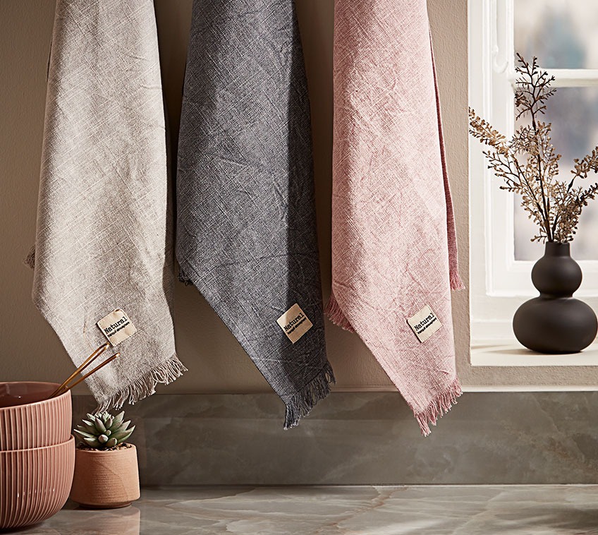 Three tea towels hanging in a kitchen