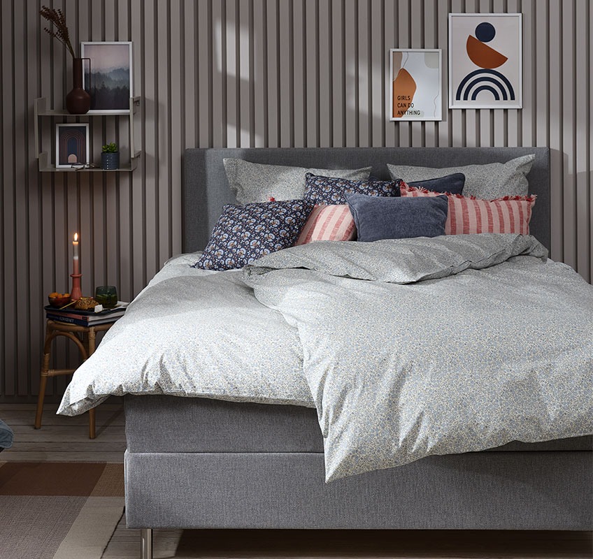 Bedroom with blue floral bed linen and decorative cushions in blue and rose colours