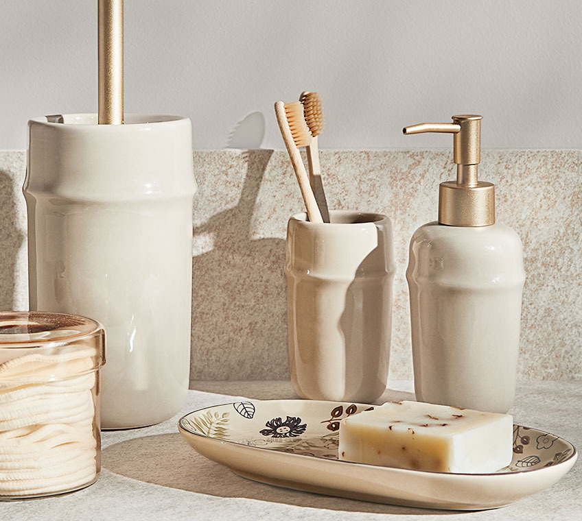 Jarrón de cristal GRUMS y set de baño con recipiente para cepillo de dientes, dispensador de jabón y escobilla BOLIDEN. Jarrón de cristal y set de baño en cerámica beige.