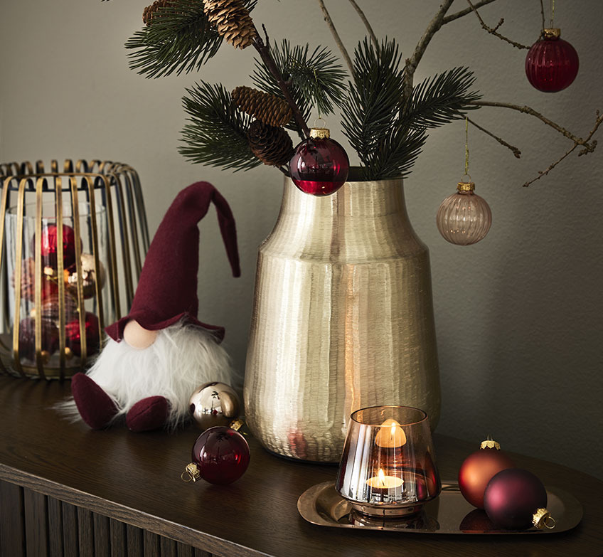 FENJA candlestick filled with STJERNE baubles, NABBI Christmas elf, MALIAS vase and FREKE tray with BRYNJE tealight holder Golden candlestick, Christmas elves and golden vase with spruce branches and Christmas baubles