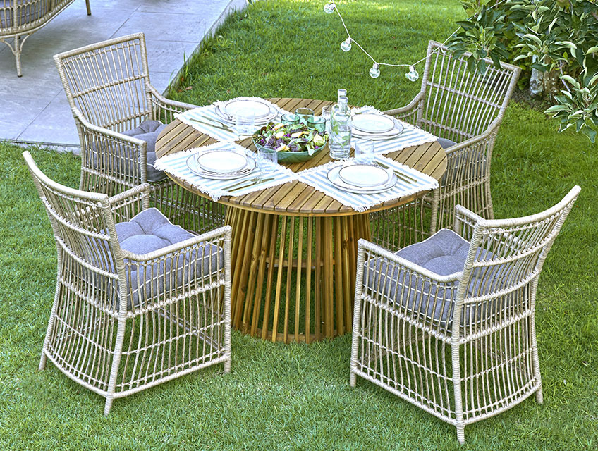 Mesa de jardín redonda con una base en el centro (centrada) y cuatro sillas de jardín situadas en un jardín 